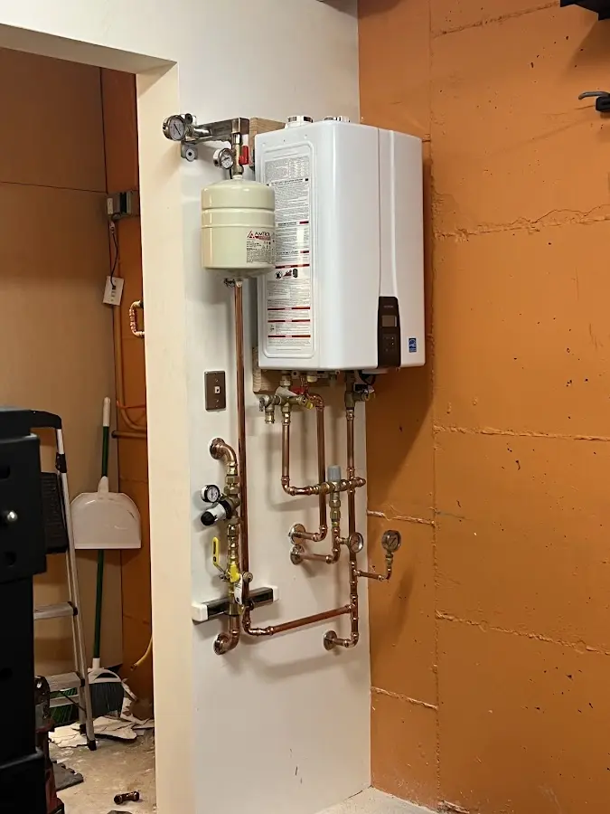 Plumbing technician inspecting water heater connections in Kronenwetter